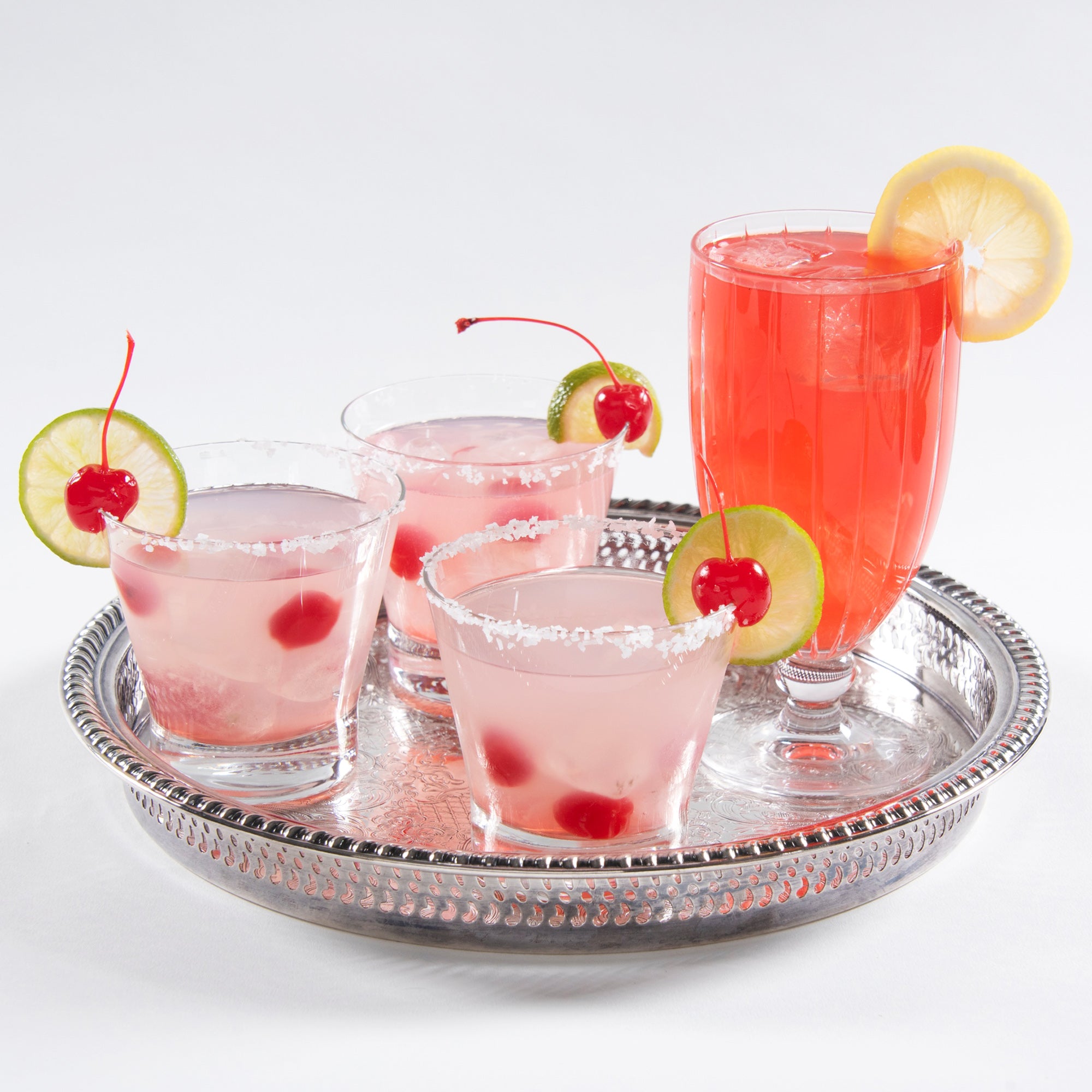 A silver tray displaying four cocktails, garnished with tequila-spiked maraschino cherries, adding a vibrant and flavorful touch to the drinks.