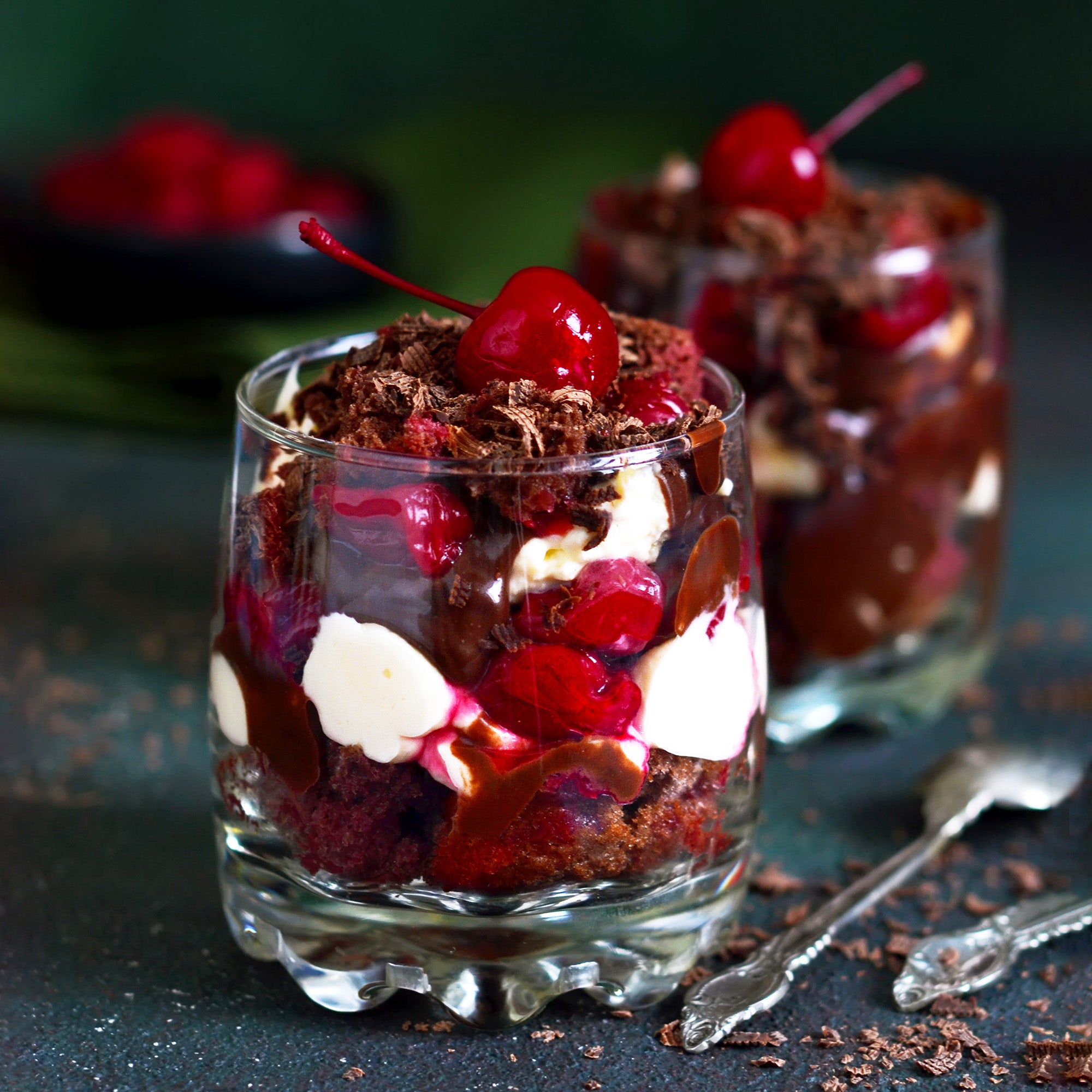 Two dessert glasses filled with chocolate and topped with tequila-spiked maraschino cherries, showcasing a decadent treat.