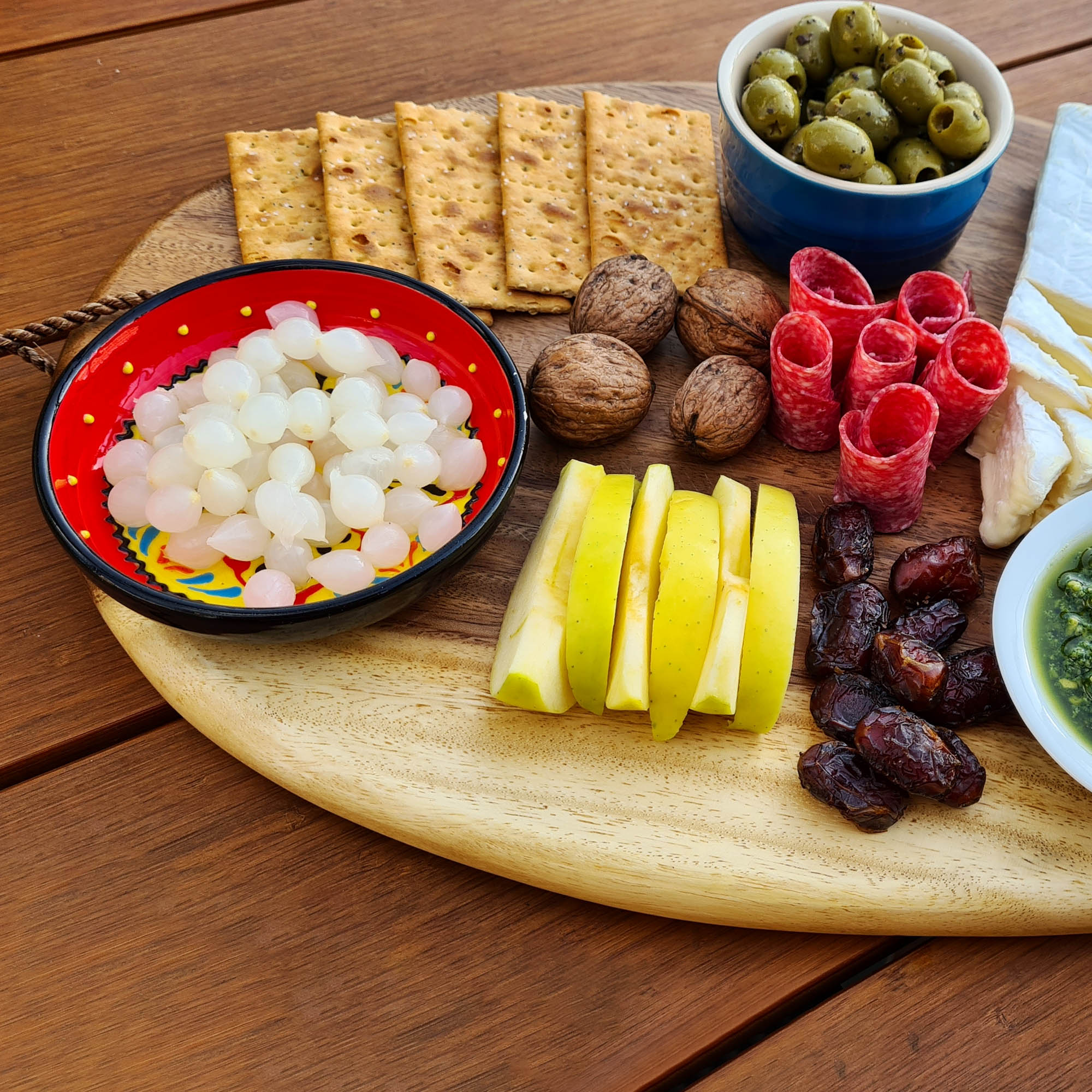 A wooden cutting board featuring a variety of appetizers, including Vermouth Tipsy Onions, perfect for entertaining.