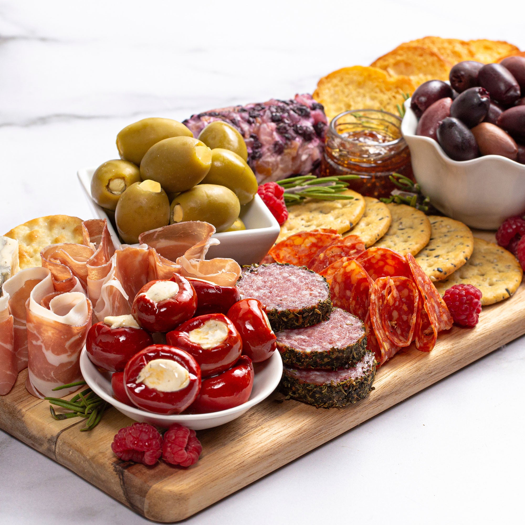 A wooden cutting board displaying a variety of foods, including gin lemon stuffed olives, perfect for appetizers and cocktails.