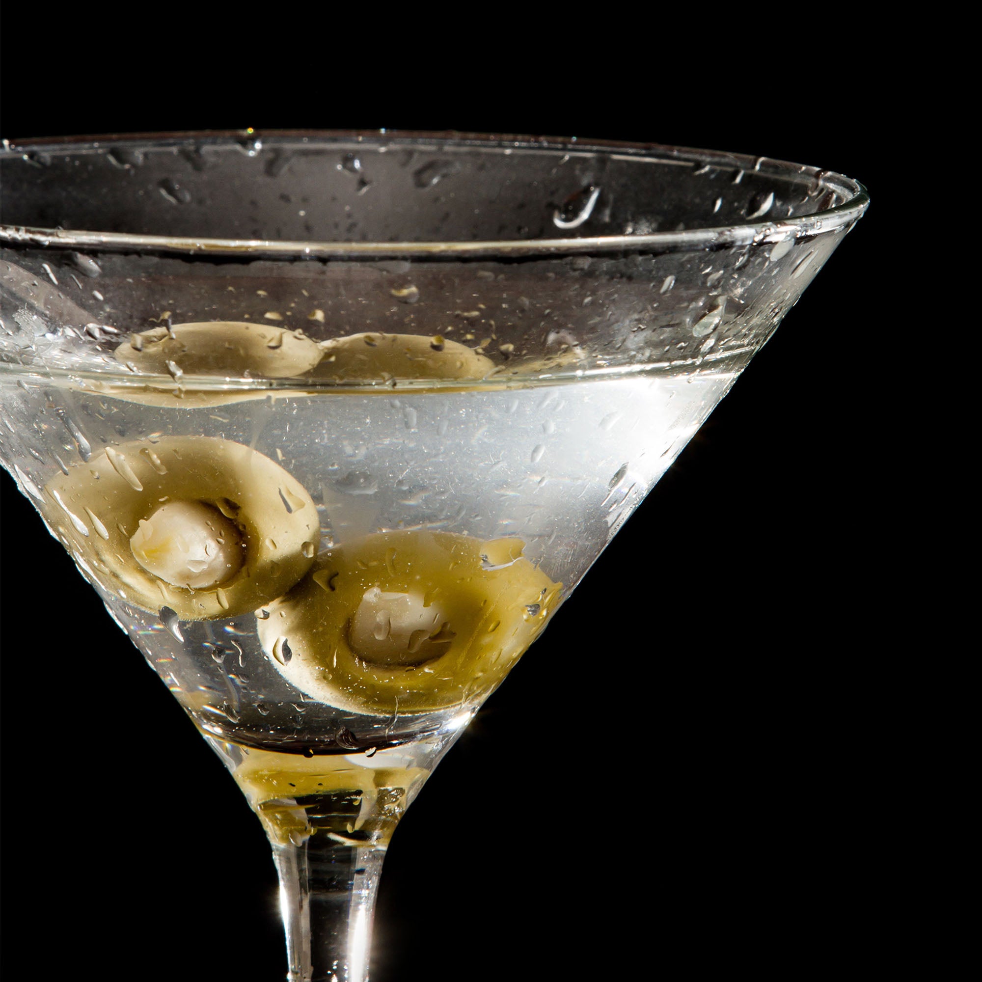 A martini glass filled with vodka and garlic-stuffed olives, showcasing an elegant garnish for cocktails.