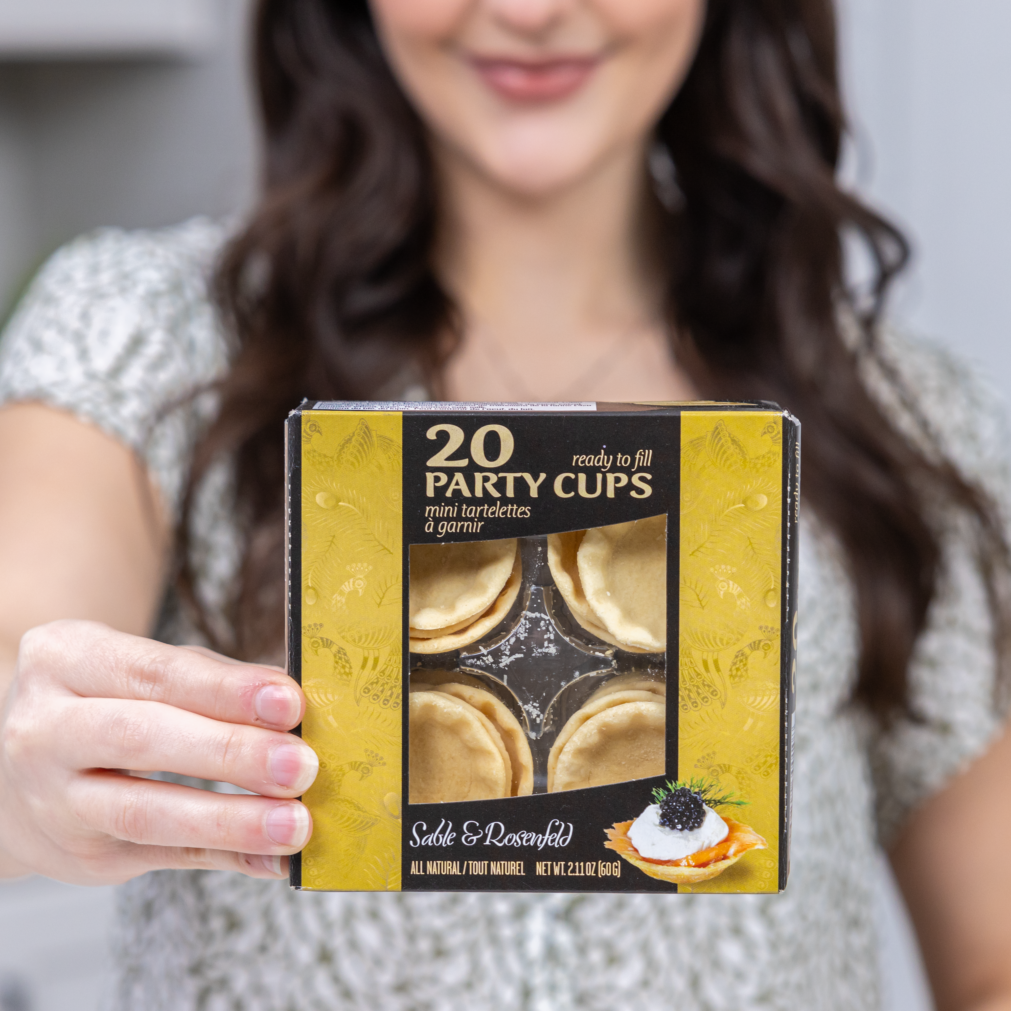 A woman holding a box of Sable & Rosenfeld 20 Party Cups, ready-to-fill mini tartelettes, perfect for appetizers and desserts.